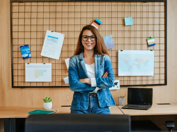 Smiling businesswoman in denim at workspace with laptop and notes, representing business services in our directory